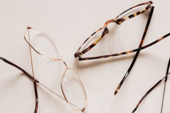 From above of fashion glasses with optical lenses for vision correction in metal shells together with pair in plastic tortoise shell placed on white table