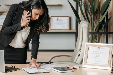 A professional woman lawyer multitasking in a modern office environment, reviewing documents.
